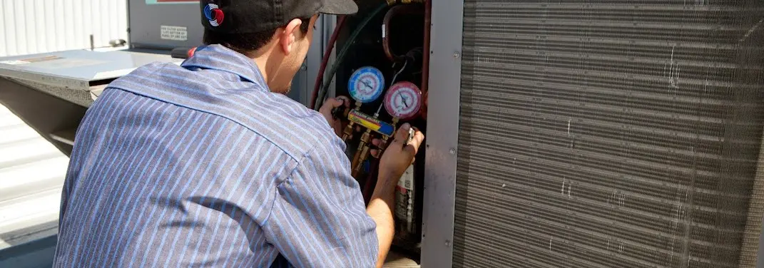 HVAC technician servicing a condenser unit in Somers